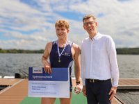 Dr. Bolling überreicht den Spendencheck an den Gewinner des U23-Rennens August Herman Wisholm (© AMEOS). 