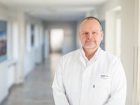 Der neue Chefarzt der Klinik für Orthopädie, Unfall- und Rheumachirurgie am AMEOS Klinikum Halberstadt ist Prof. Dr. med. Ralph Gaulke. Er steht im Arztkittel in einem Flur und lächelt in die Kamera.