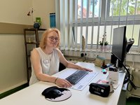 Ärztin sitzt am Schreibtisch und lächelt in die Kamera