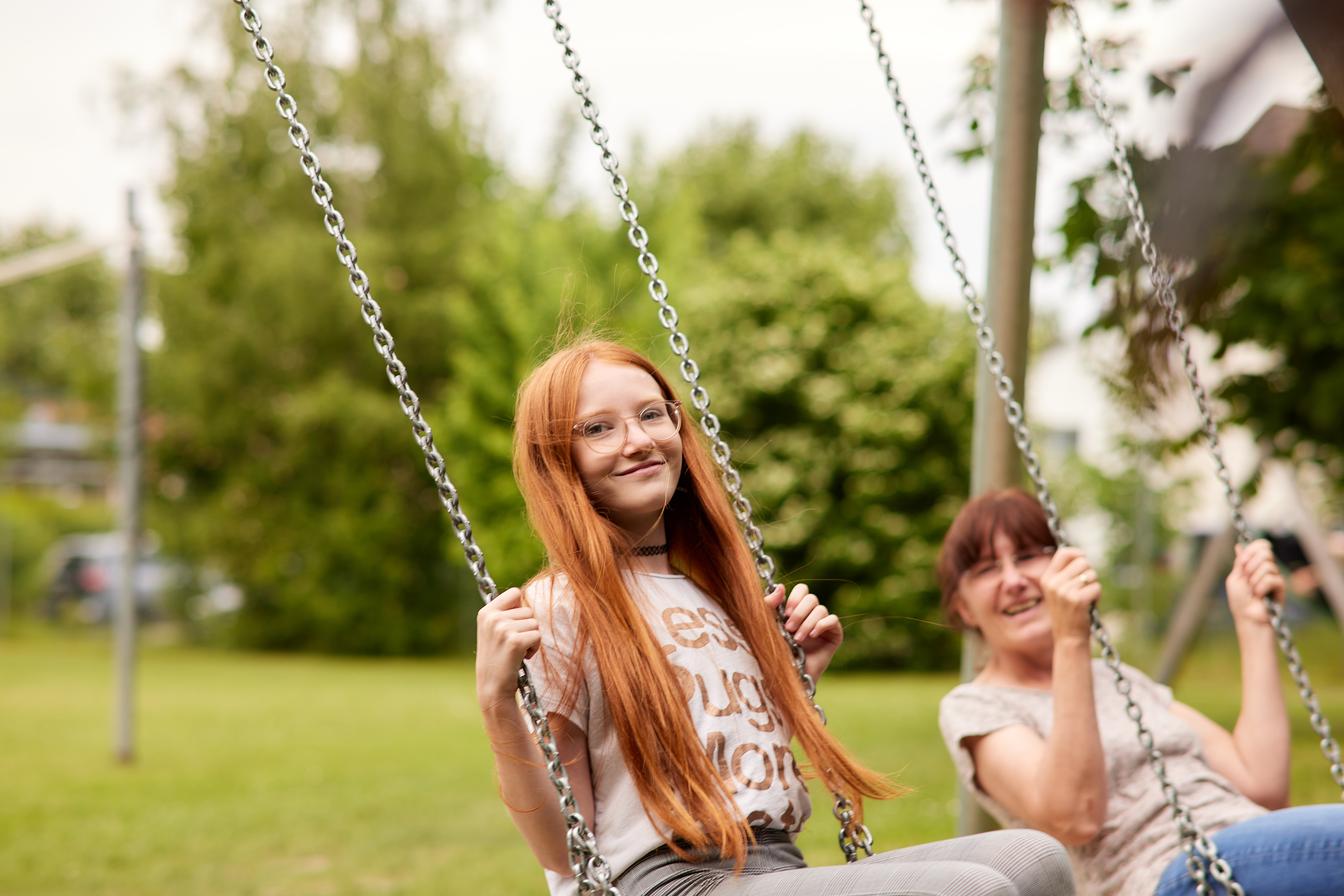 Ein Mädchen und eine Frau schaukeln nebeneinander